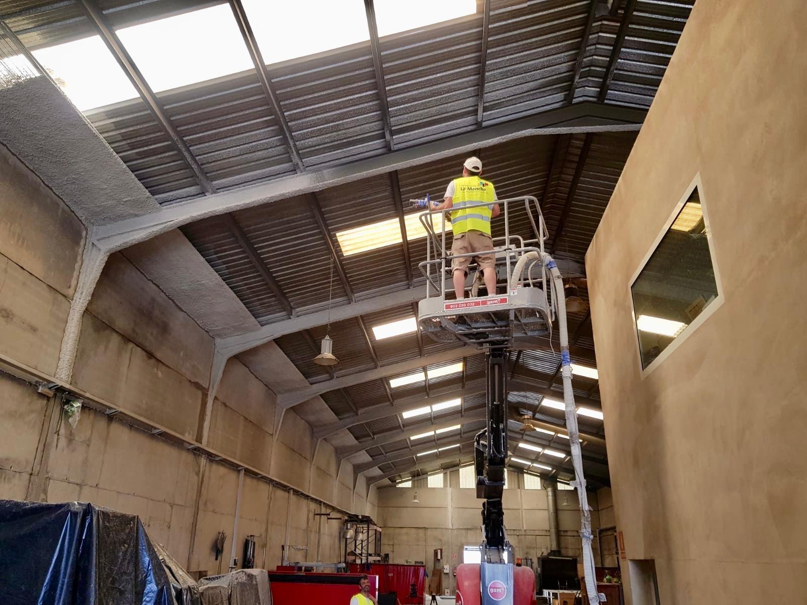 Operario de Ignifugaciones Barna aplicando mortero ignífugo proyectado sobre la cubierta metálica de una nave industrial